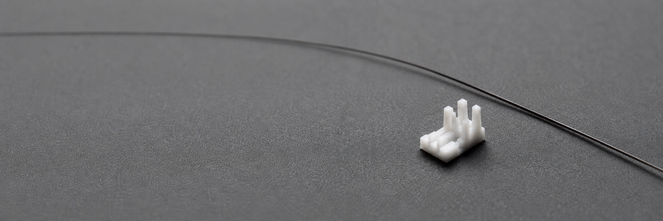 Precision white micro-moulded plastic component on grey surface